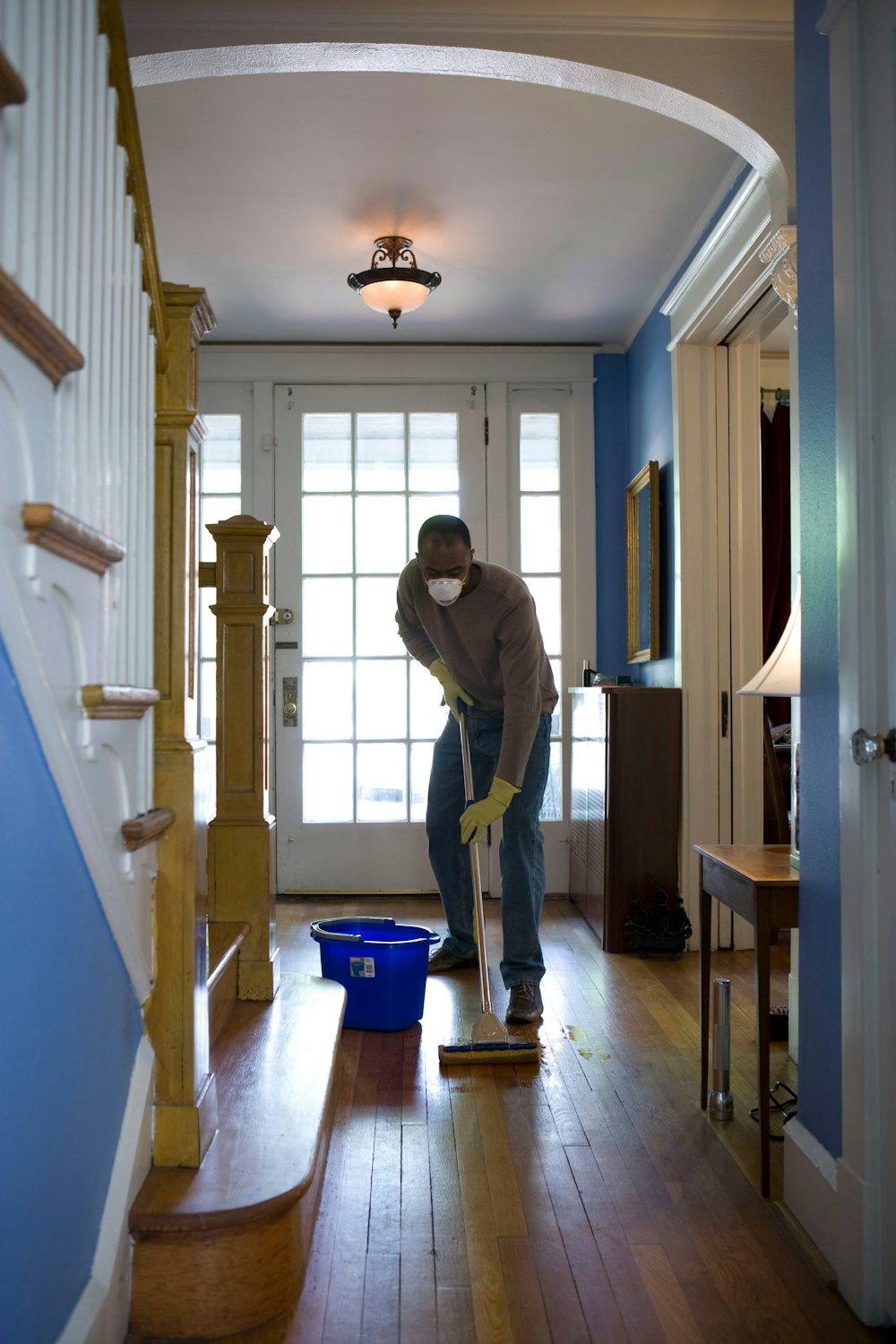 This African-American man was in the process of damp-mopping his home’s entrance way. In this way airborne particulates including dust and pollen, could be removed from the inside of his home, thereby, reducing the detrimental effects these substances have upon the respiratory system of his family members. These irritants can sometimes result in sinus infections, and asthma. 