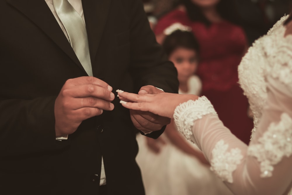 man in black suit jacket holding womans hand