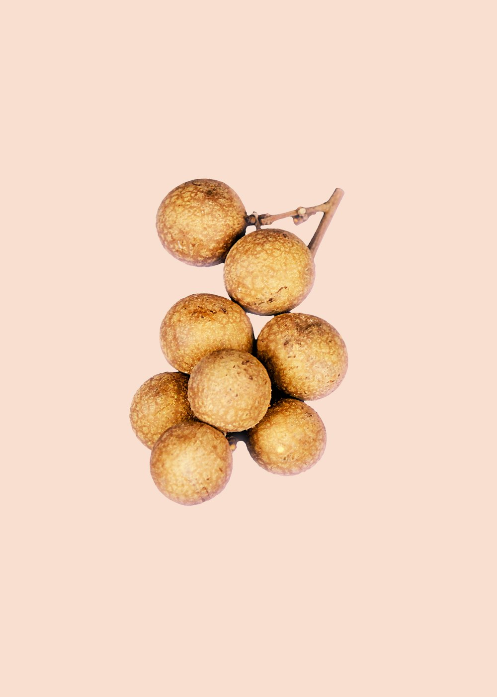 A bunch of longan fruit on top of a peach background