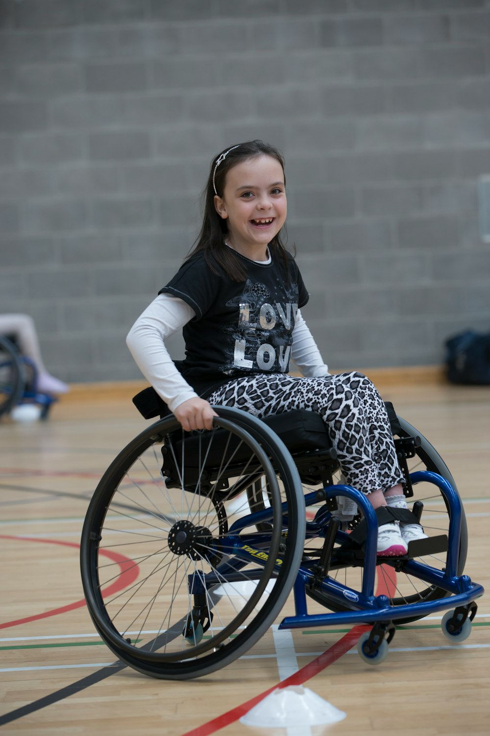 Little girl participating in a wheelchair basketball training session.