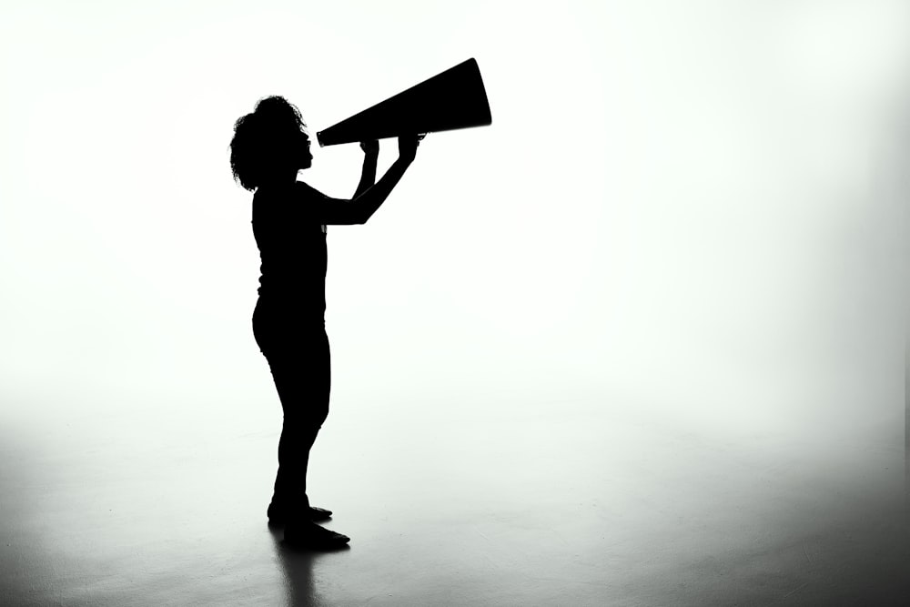 Silhouette of a female holding a analog megaphone.