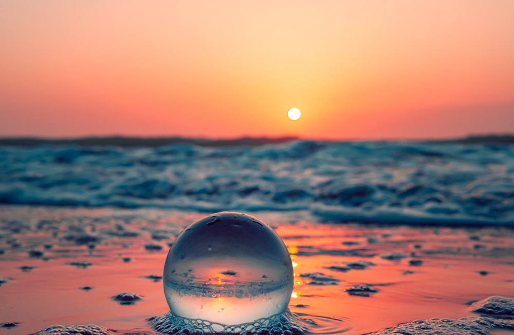 Relaxing Scene With Glass Ball On Calm Ocean Beach At Sunrise