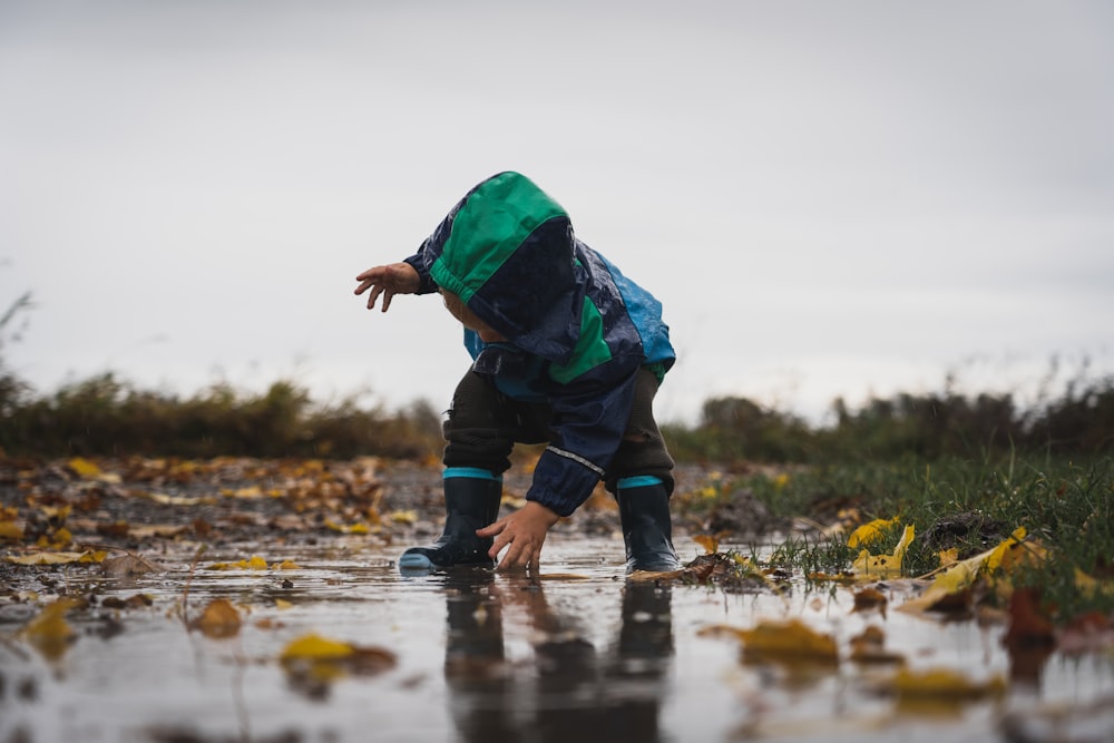Cute little child playing in a puddle during rain