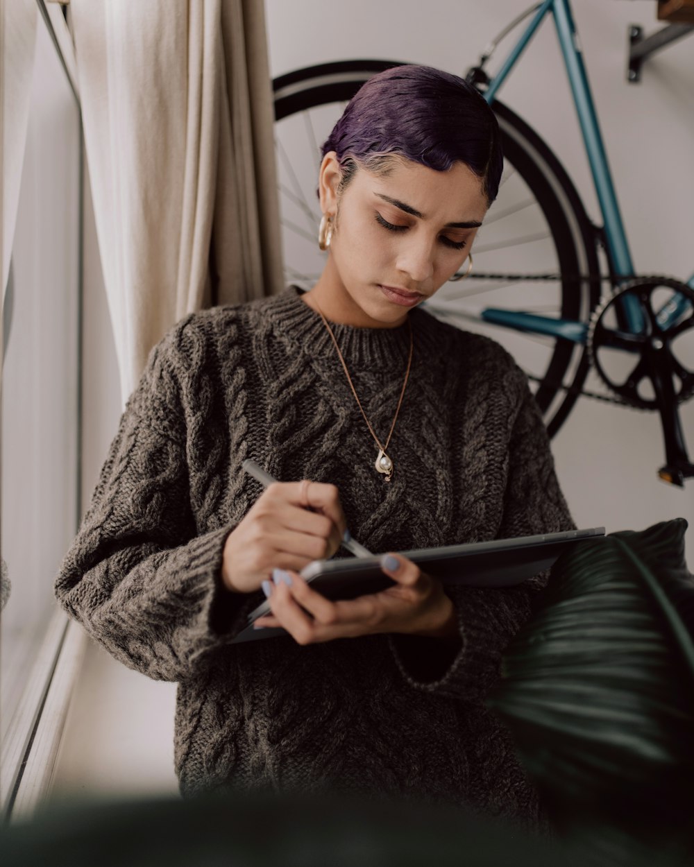 woman female tech entrepreneur working near a window on an iPad designing her dream impact driven business