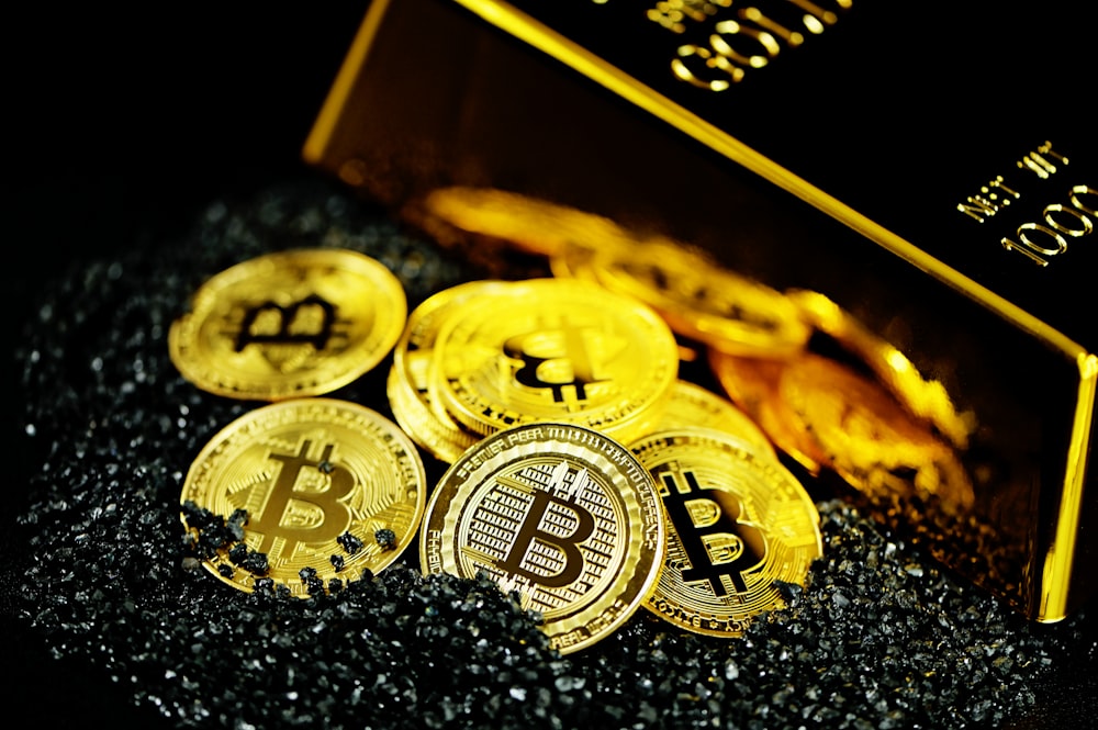 A pile of Bitcoins on black crystals next to a gold bullion