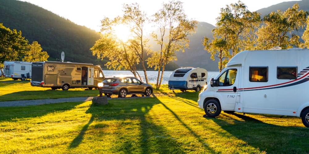 Happy camper sunset, motorhome by lake and mountains