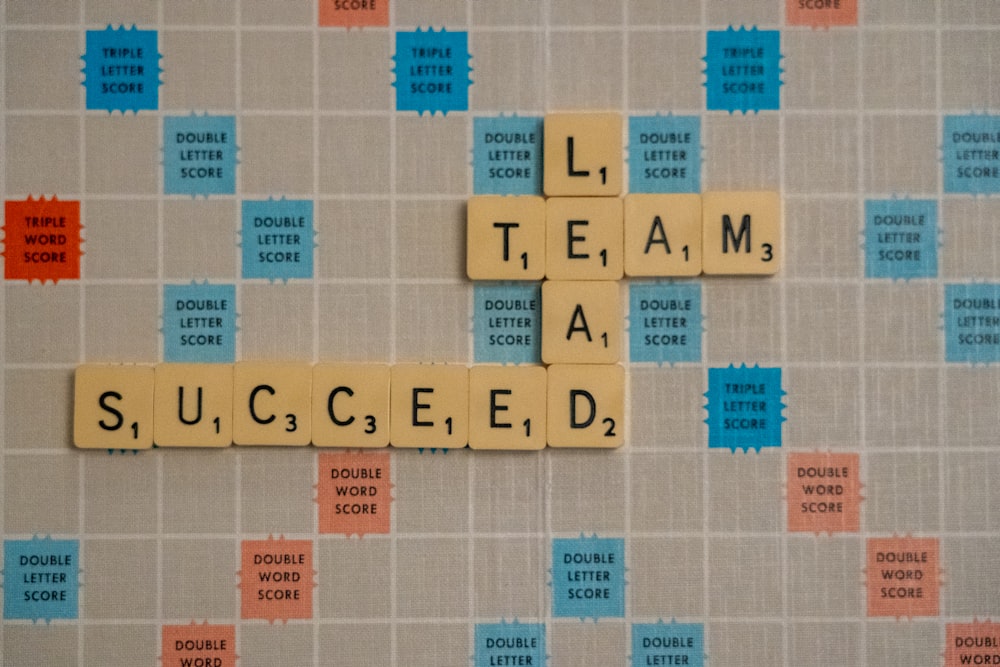 Team Lead Succeed, the title of a business book by Nick Fewings, Teamologist at Ngagementworks, spelled out in scrabble letters.