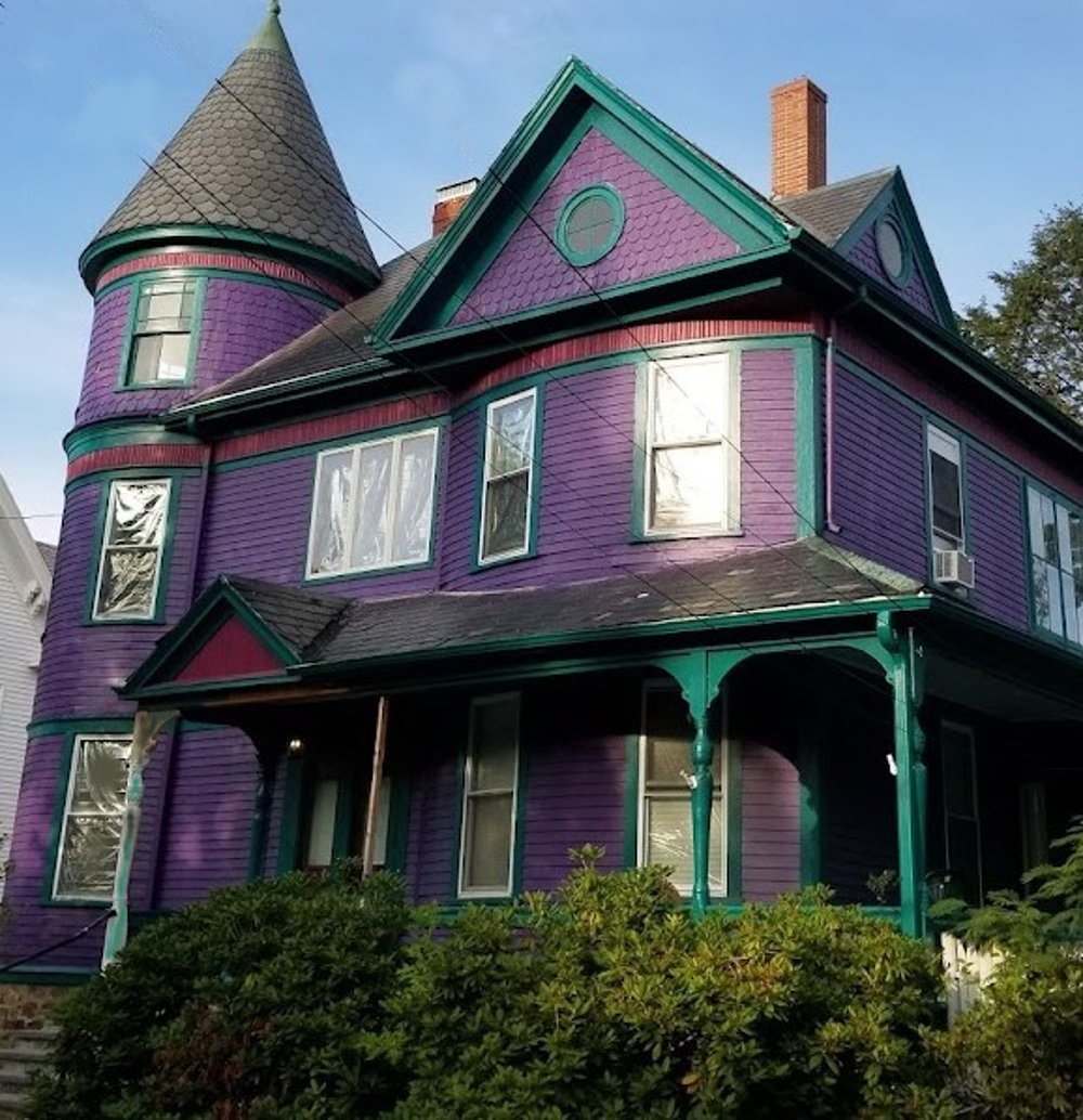 large victorian style house painted in a deep purple with trim in spruce and accents of berry