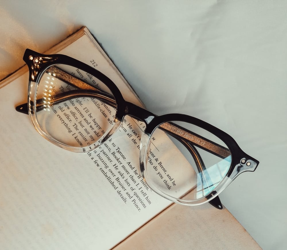 Black Framed Eyeglasses on White Open Book.
